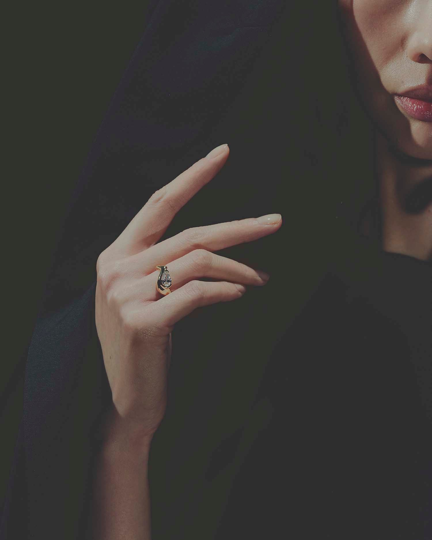 Close-up of a hand wearing a gold diamond ring with a dark background