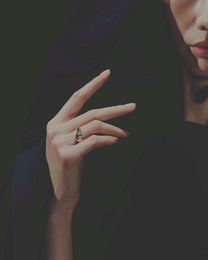 Close-up of a hand wearing a gold diamond ring with a dark background