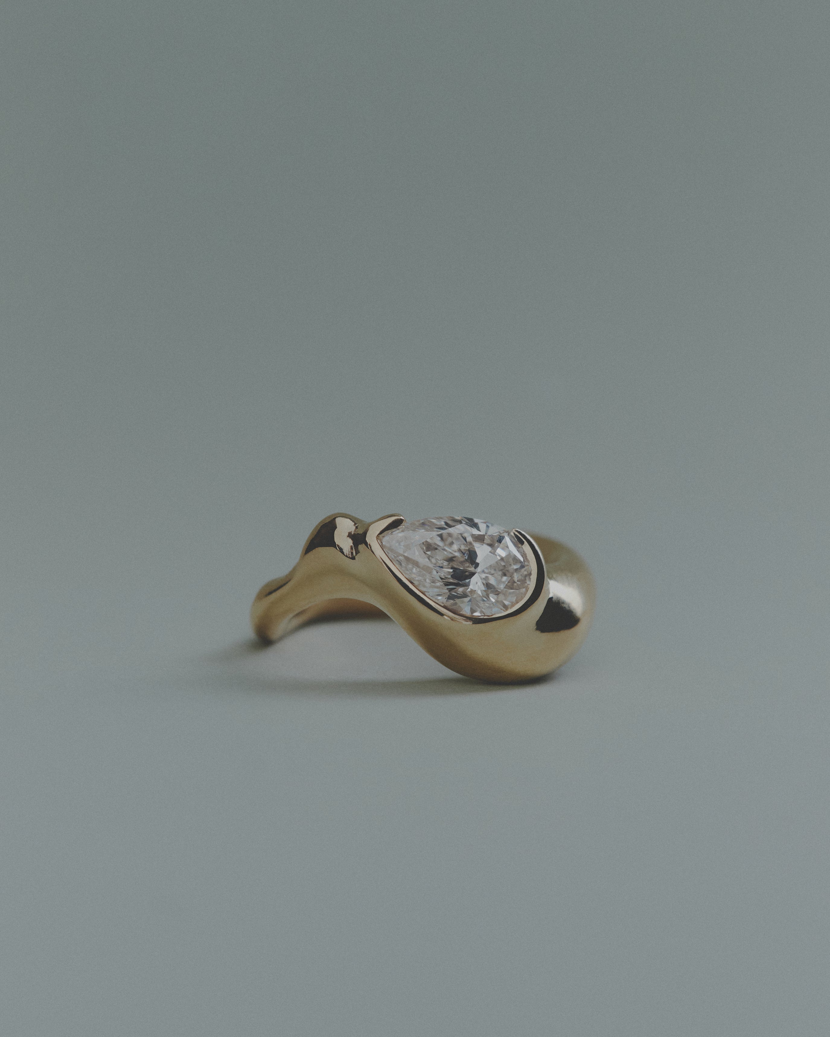 Gold ring with a pear diamond on a gray background