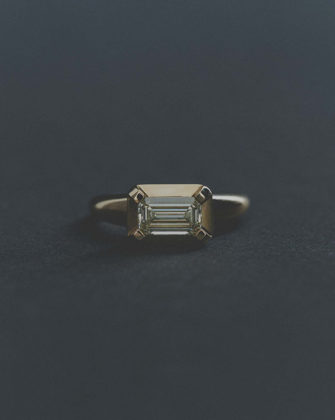 Gold ring with a rectangular diamond on a dark gray background