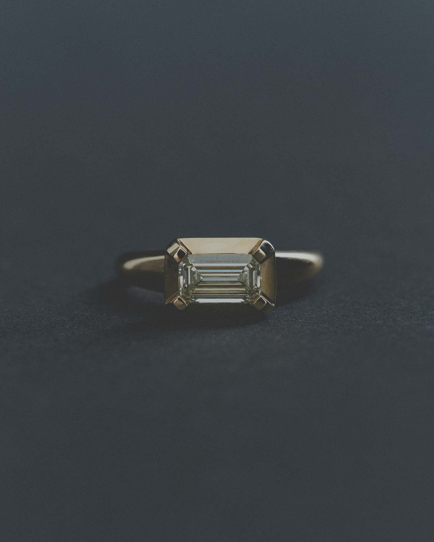 Gold ring with a rectangular diamond on a dark gray background