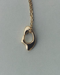 Gold necklace with a unique pendant on a gray background