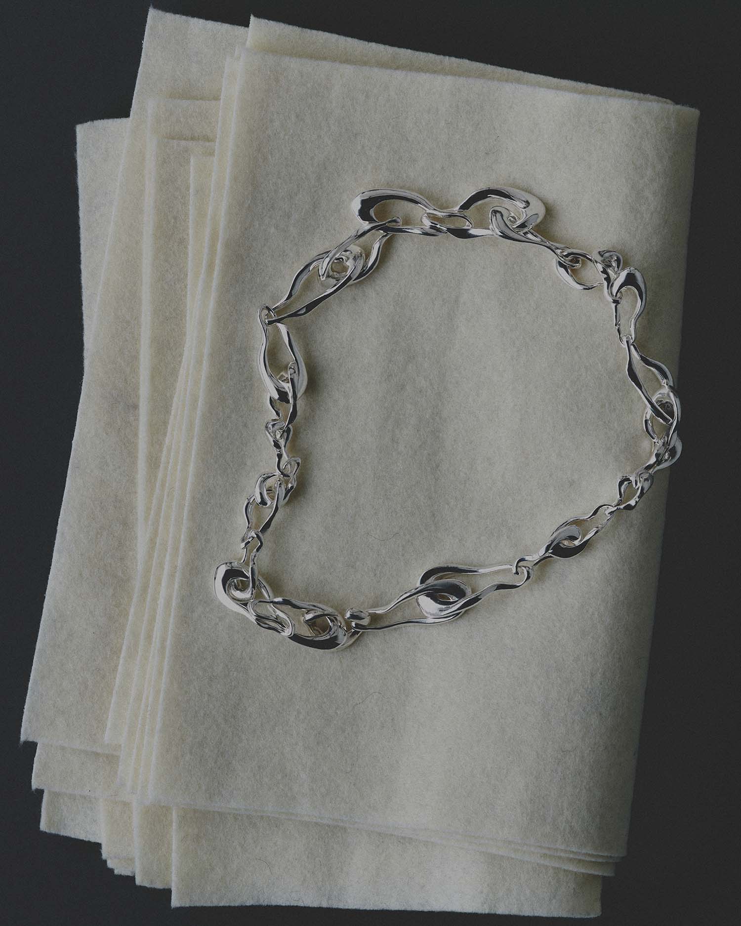 Silver necklace on a stack of white papers with a dark background