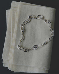 Silver necklace on a stack of white papers with a dark background