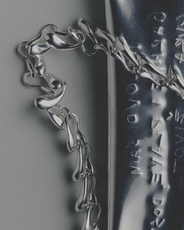 Close-up of a silver necklace with engraved text on a gray background