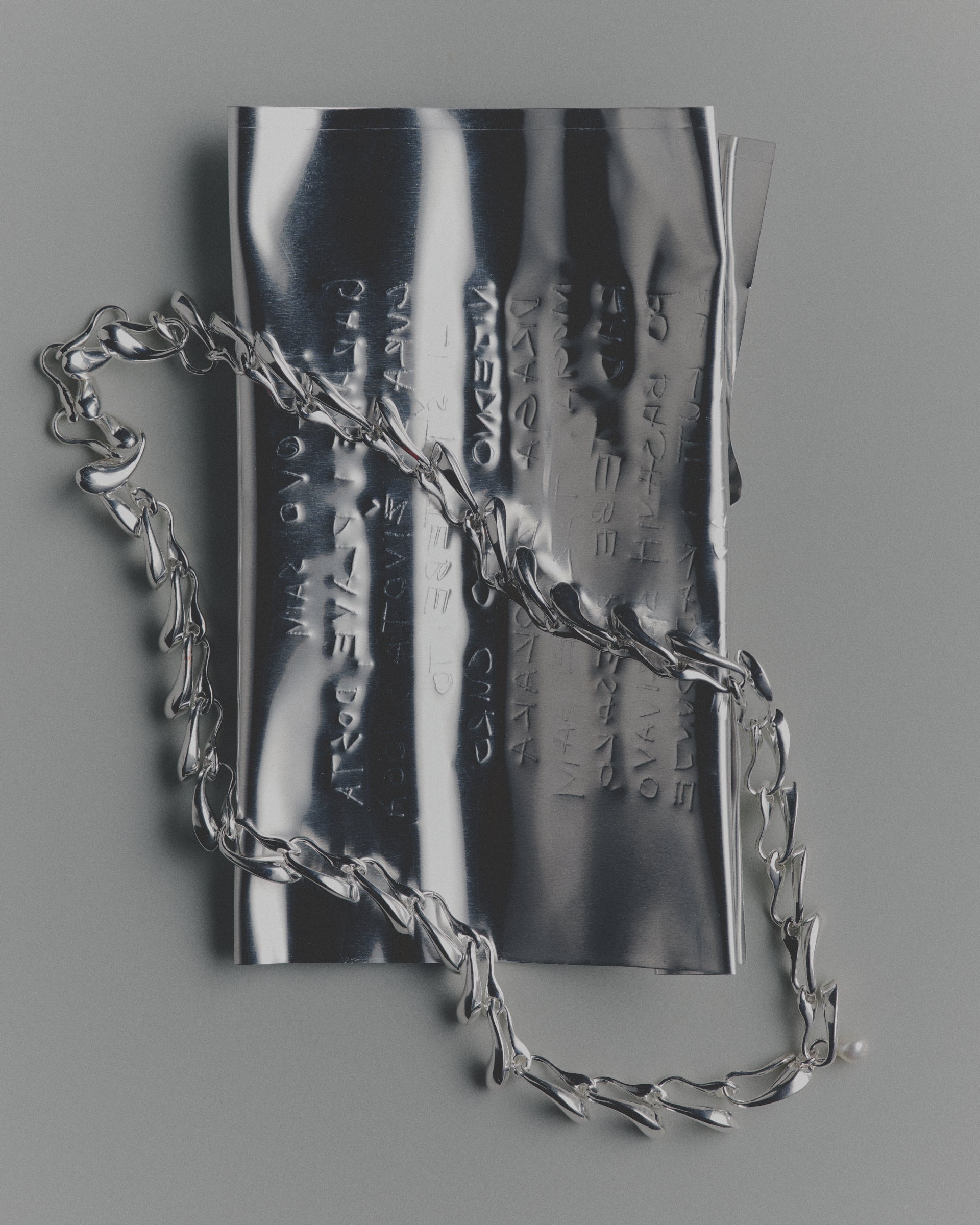Silver chain necklace on a reflective surface