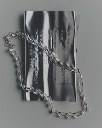 Silver chain necklace on a reflective surface
