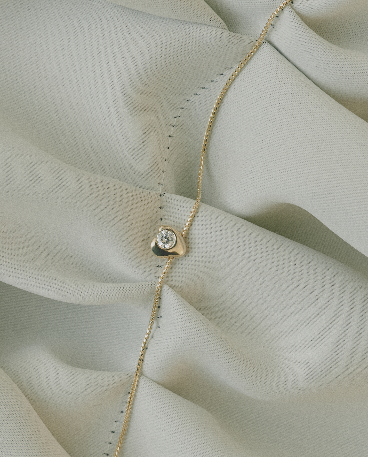 Gold necklace with a diamond pendant on a light fabric background