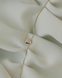 Gold necklace with a diamond pendant on a light fabric background