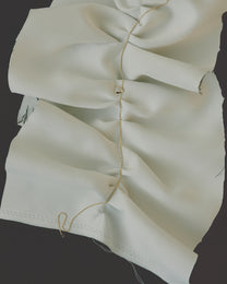 Close-up of a hold diamond necklace on beige fabric with visible stitching on a dark background