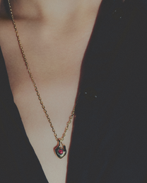 Gold necklace with a red gemstone pendant on a dark background