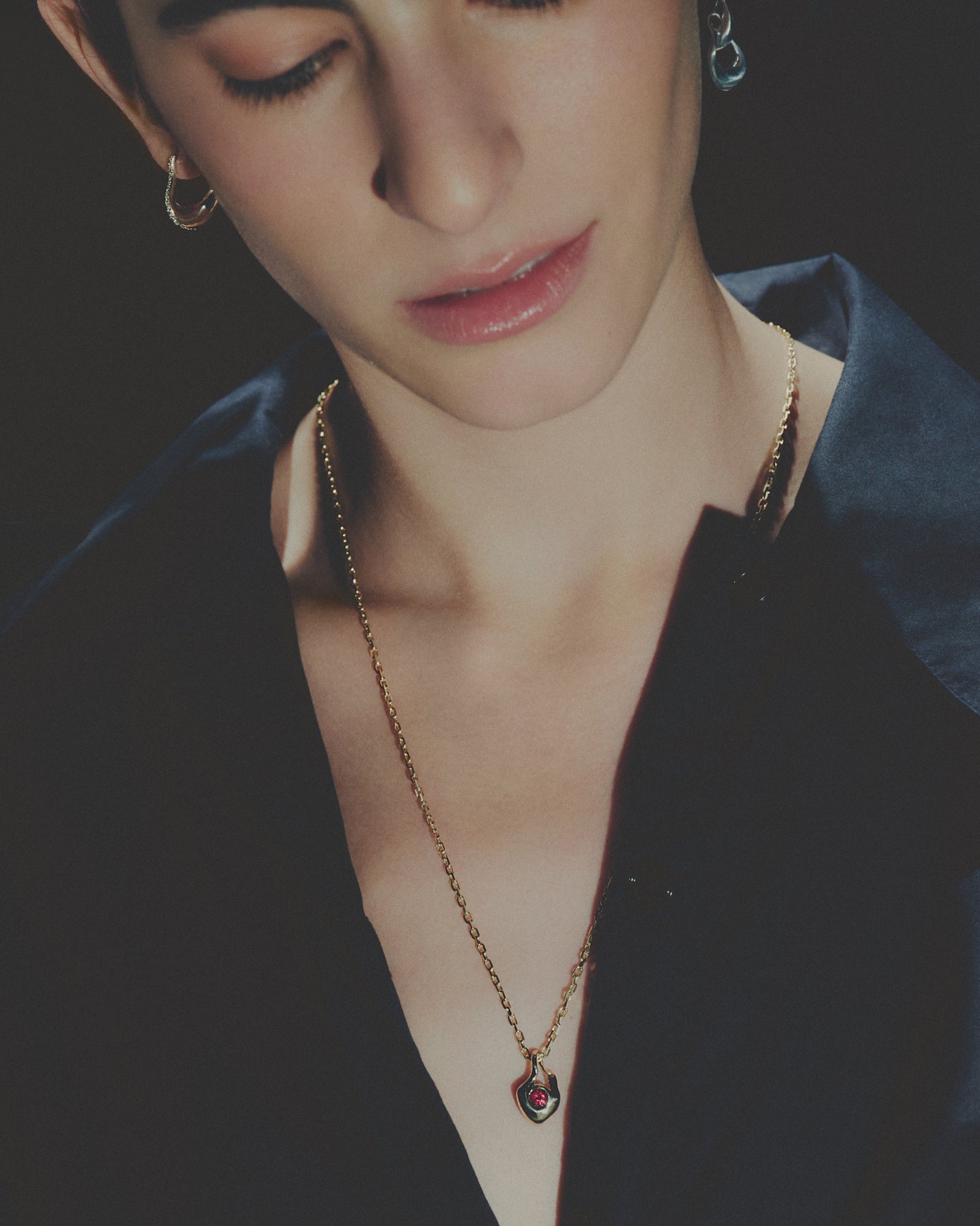 Close-up of a person wearing a gold necklace with a dark background