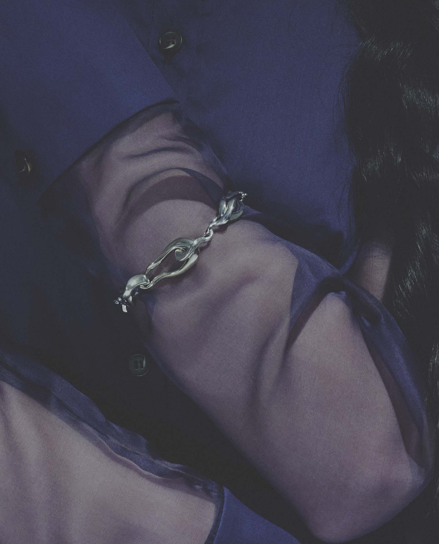 Close-up of a hand wearing a silver bracelet with a blue coat sleeve.