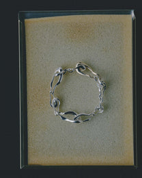 Silver bracelet on a textured beige sponge with a black border