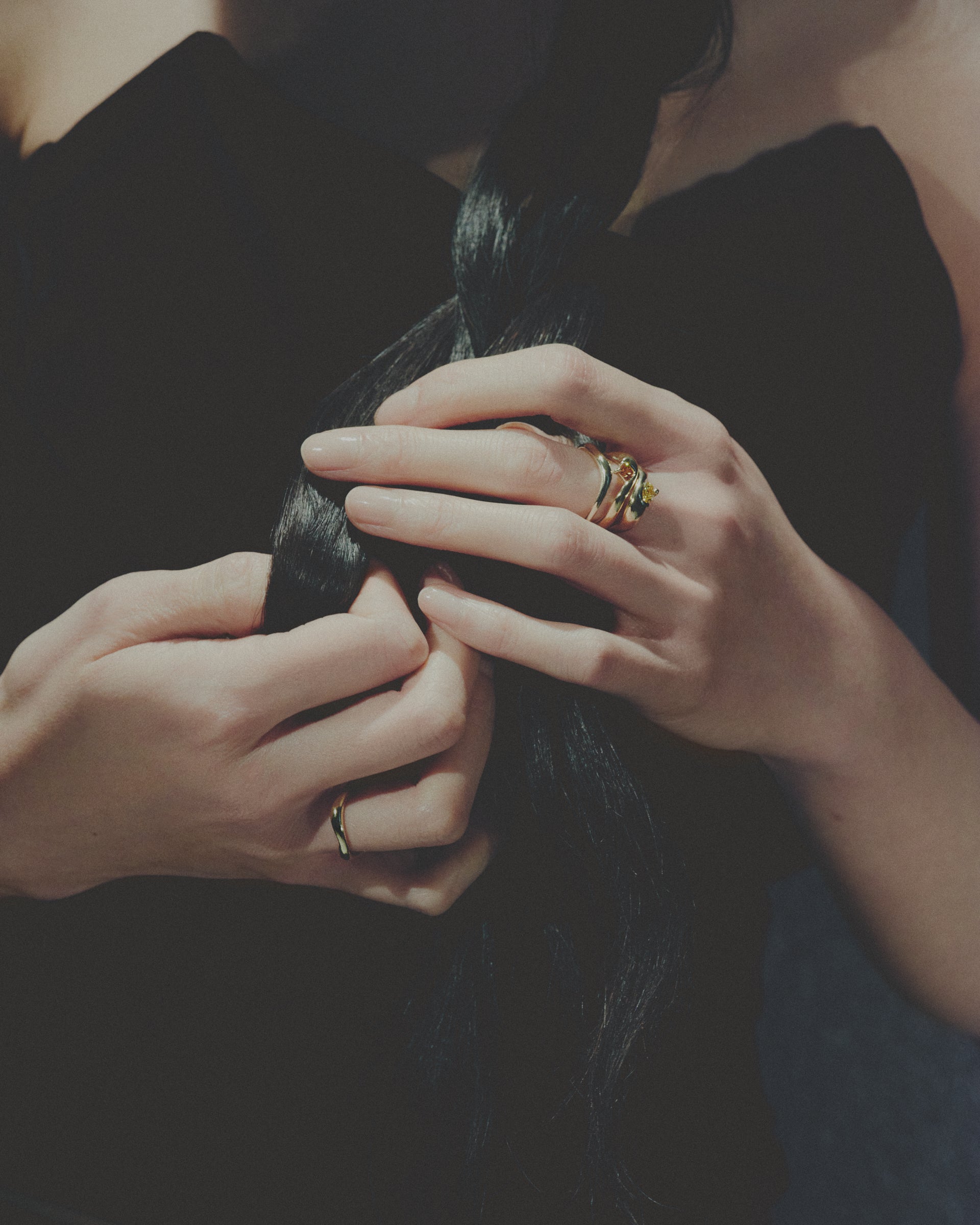 Close-up of hands with rings holding a dark fabric