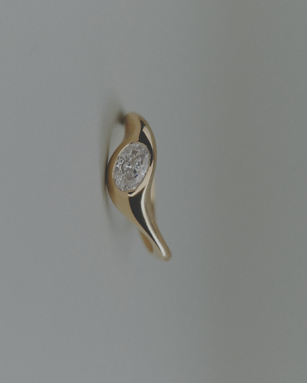 Gold ring with an oval diamond on a light gray background