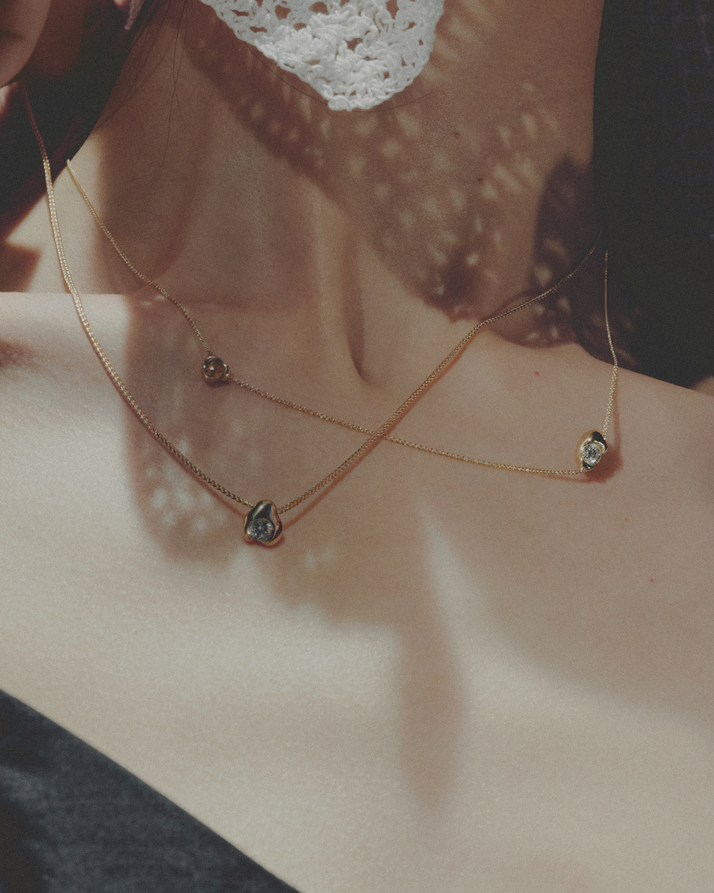 Fine chain necklace with organic-shaped pendants on a person&#39;s neck.