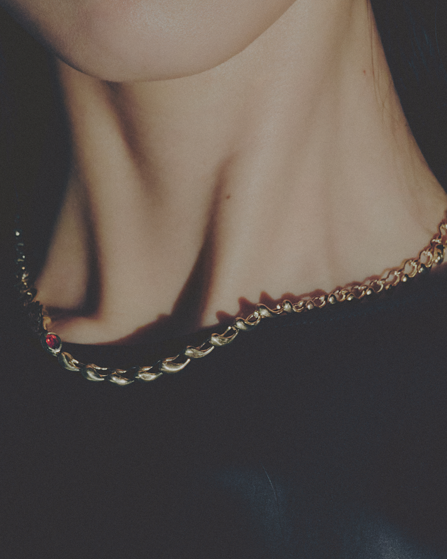 Close-up of a gold necklace on a neck against a dark background
