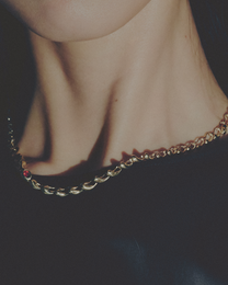 Close-up of a gold necklace on a neck against a dark background