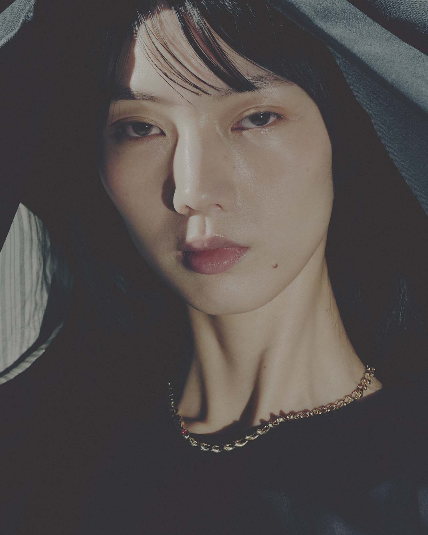 Close-up of a person wearing a gold necklace with a dark background