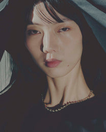 Close-up of a person wearing a gold necklace with a dark background