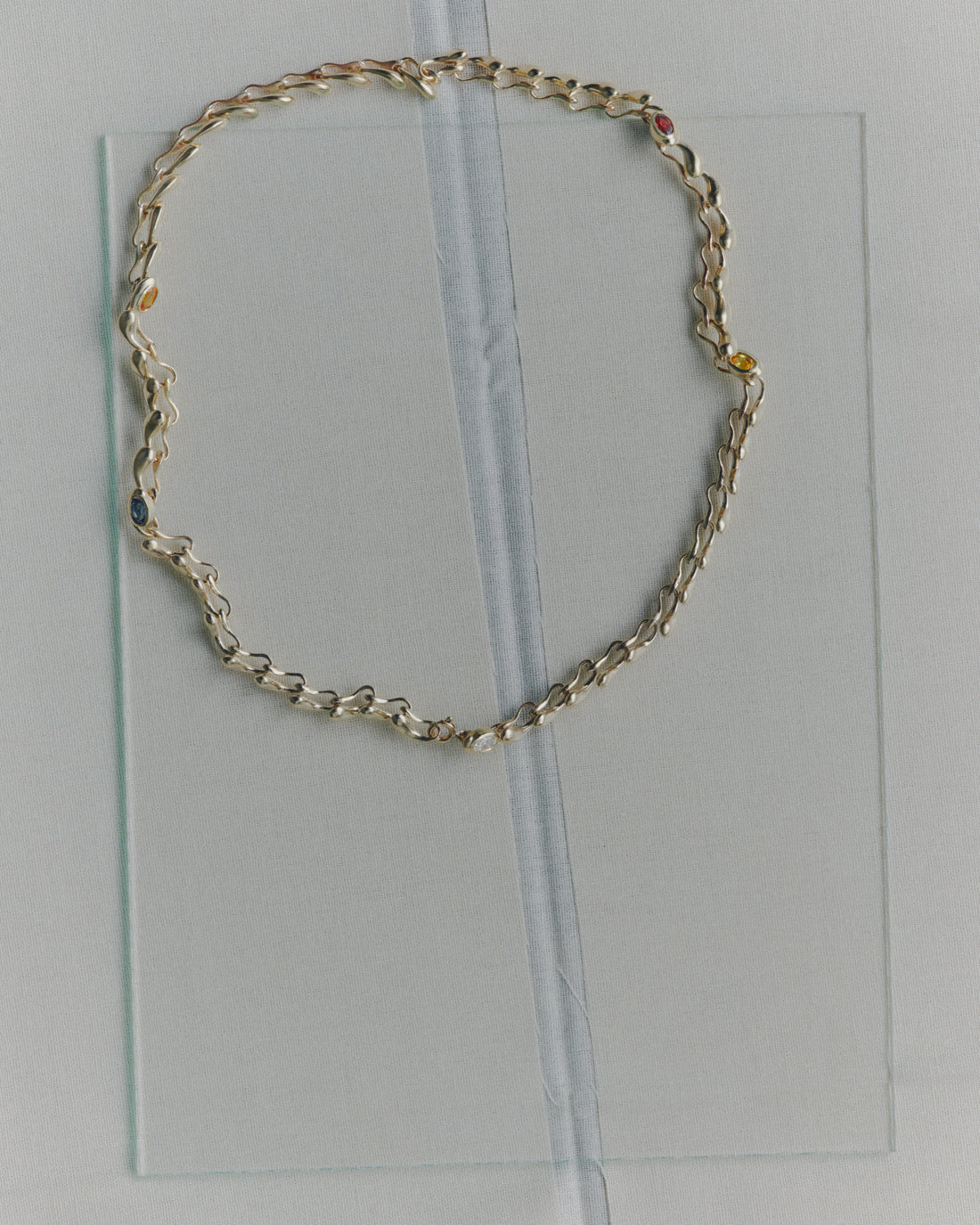 Gold chain necklace on a clear plastic sheet