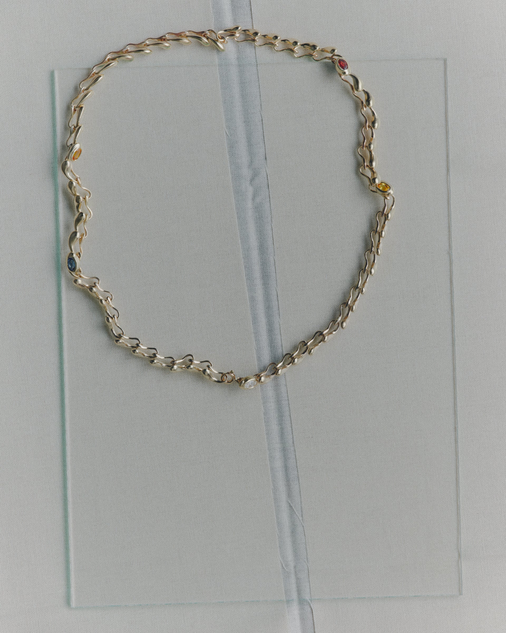Gold chain necklace on a clear plastic sheet