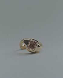 Gold ring with a unique design and large rectangular brown diamond on a gray background