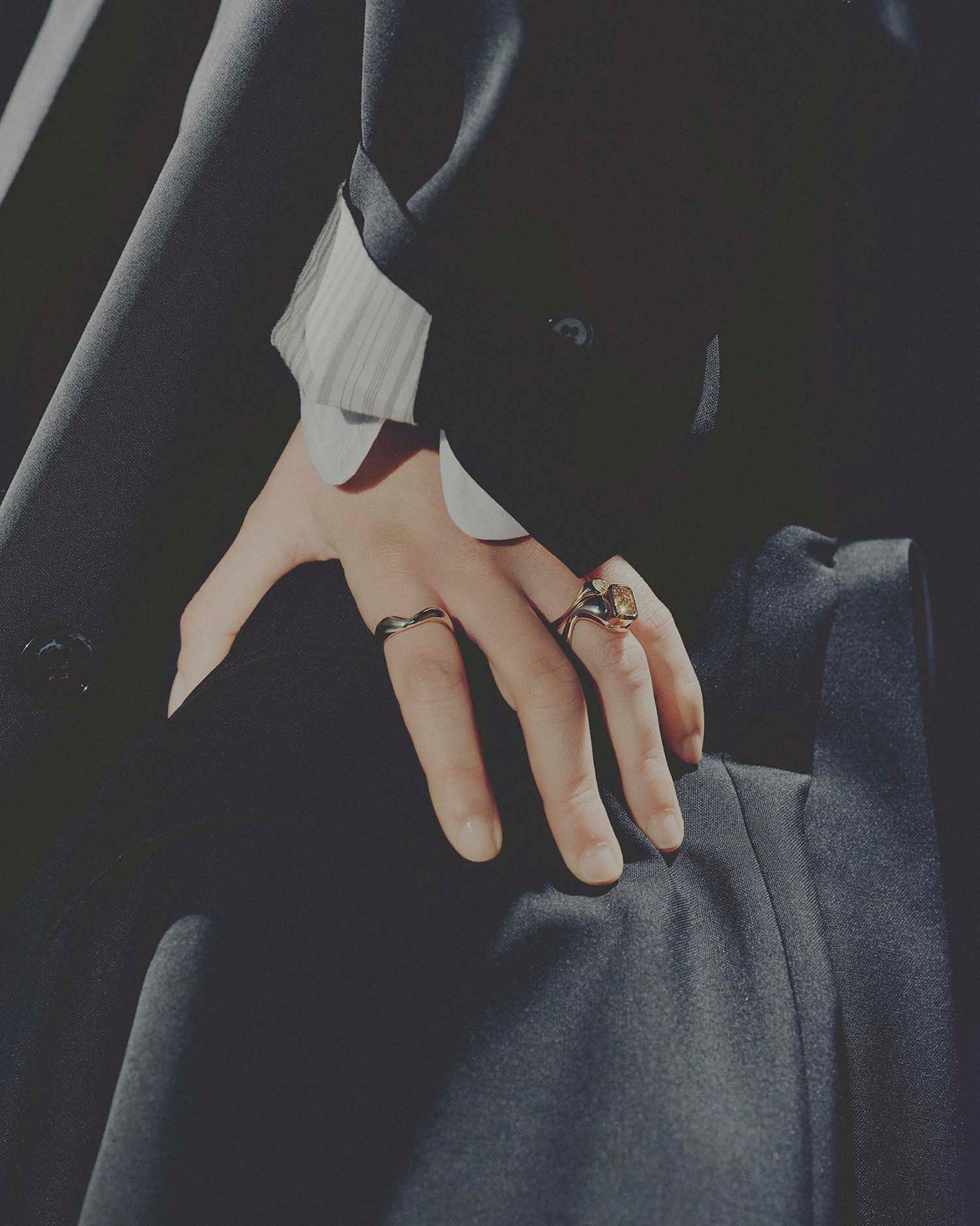 Close-up of hands wearing rings with a dark background
