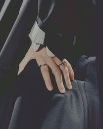 Close-up of hands wearing rings with a dark background