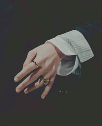 Close-up of a hand wearing two rings on a dark background